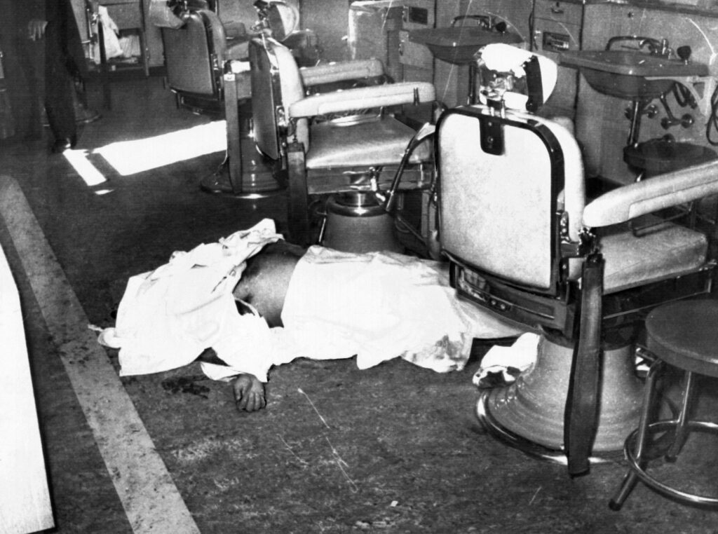 Racketeer Albert Anastasia, former 'Lord High Executioner' for 'Murder, Inc.', lies dead on the floor of the barber shop of the