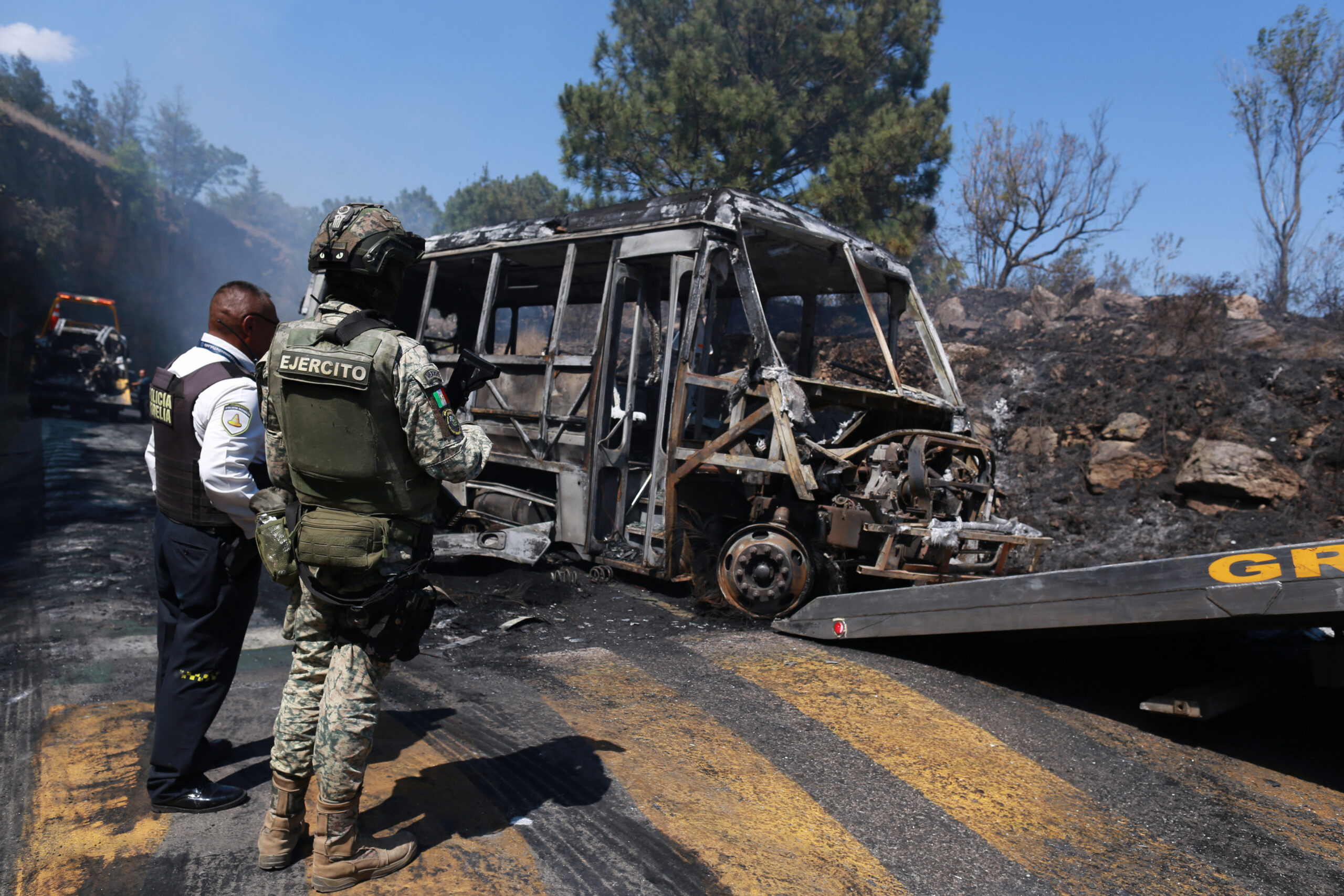 In Coíntzio, Michoacán, Mexican officials work to clear the charred remains of a bus. The vehicle was set on fire to block the road—a “narco blockade”—following the death of cartel boss Nemesio Oseguera Cervantes, also known as “El Mencho.” Associated Press