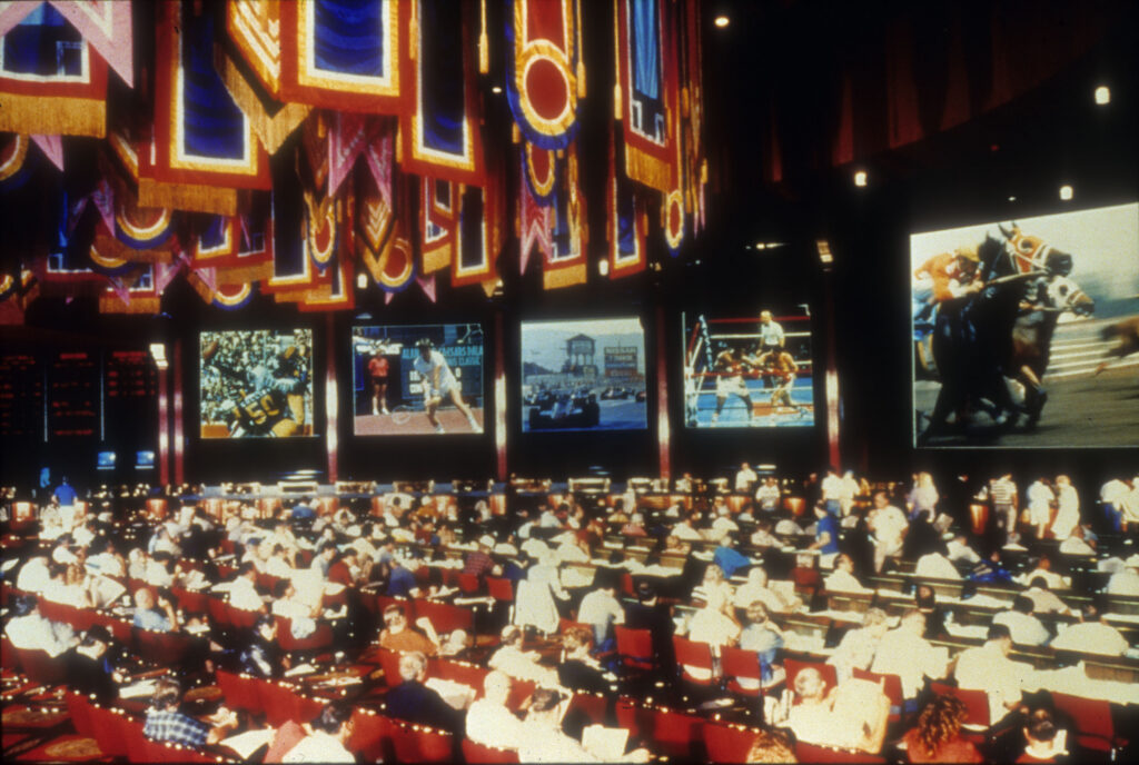 Bettors sit and watch their wagers play out in the Olympiad Race and Sports Book at Caesars Palace, 1980s. Special Collections and Archives, University Libraries, University of Nevada, Las Vegas